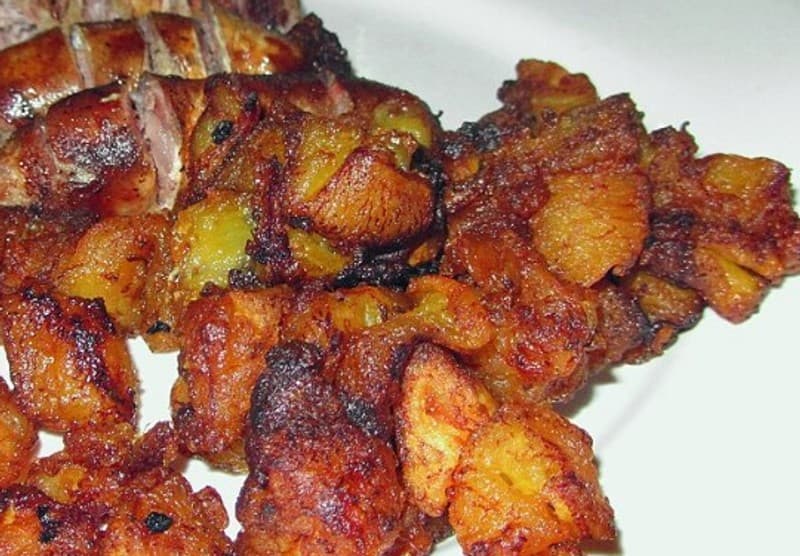 Potongan pisang raja goreng disajikan di atas piring putih dengan sedikit saus di samping.