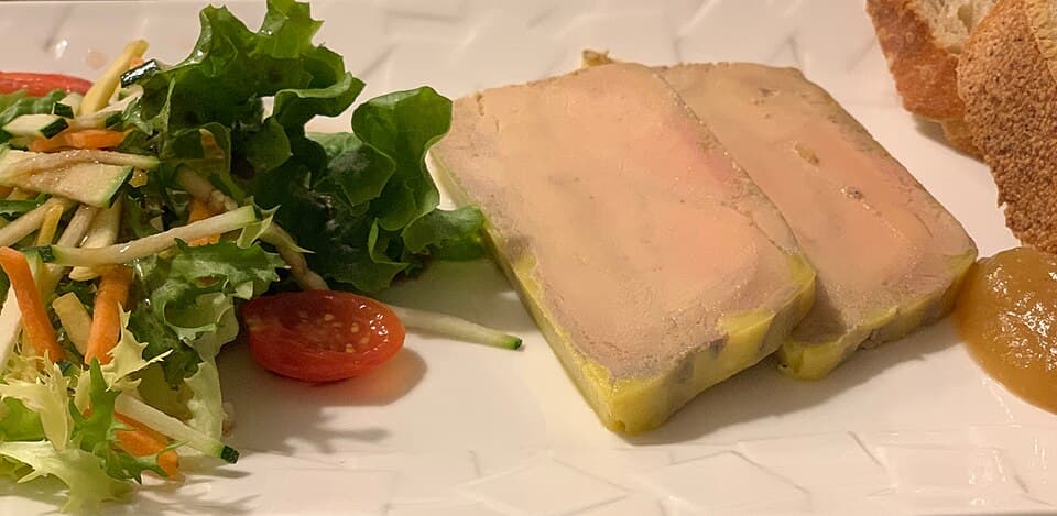 兩片淡色肝臟 terrine 搭配沙拉、麵包和醬料。
