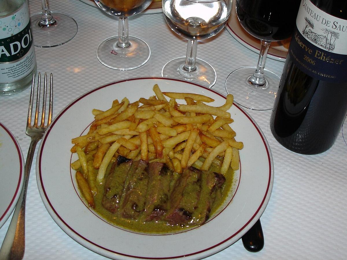 Teller mit gebratenen Steakscheiben und einem Stapel knuspriger Pommes Frites.