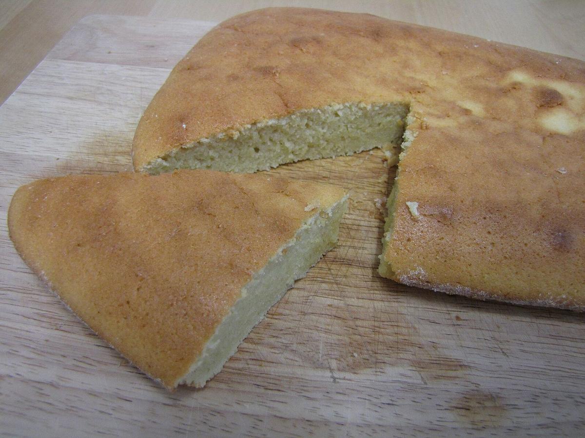 Ein einfacher rechteckiger Kuchen mit einem herausgeschnittenen Stück auf einem Holzbrett.