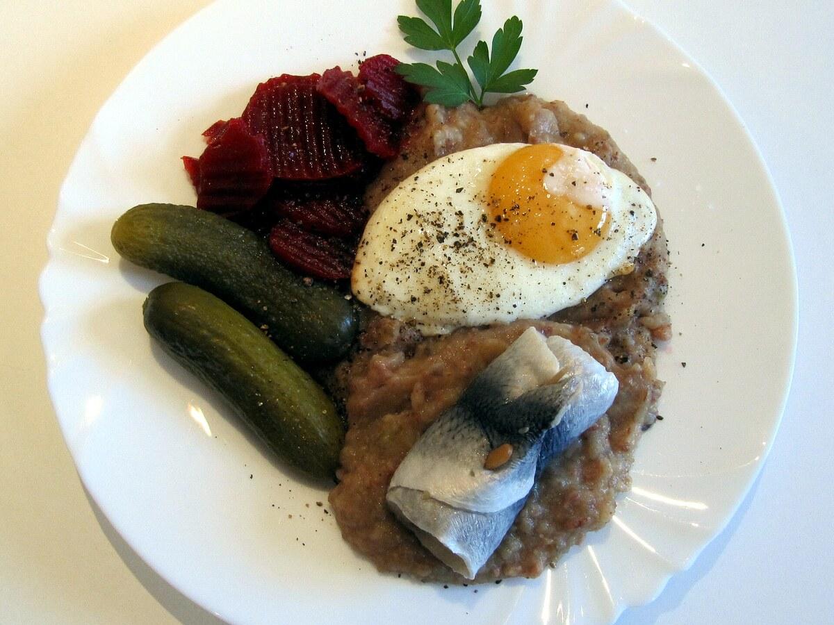 Hash rosado de papas y carne en conserva con huevo frito, remolachas, pepinillos y arenque.