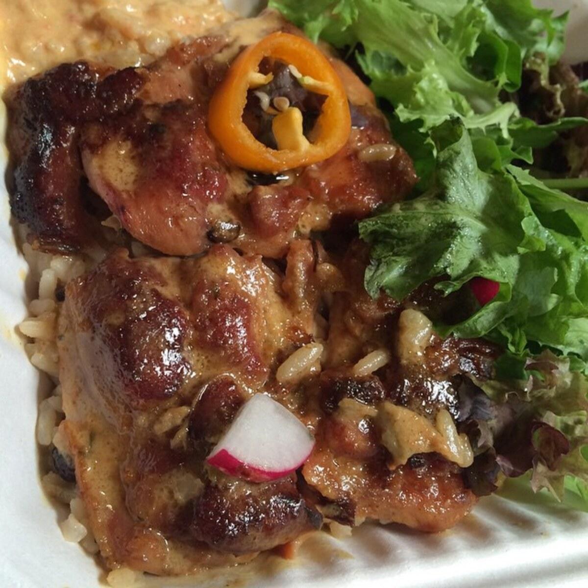 Gambar dekat ayam yang dibakar dan nasi dimasak bersama dengan rempah.