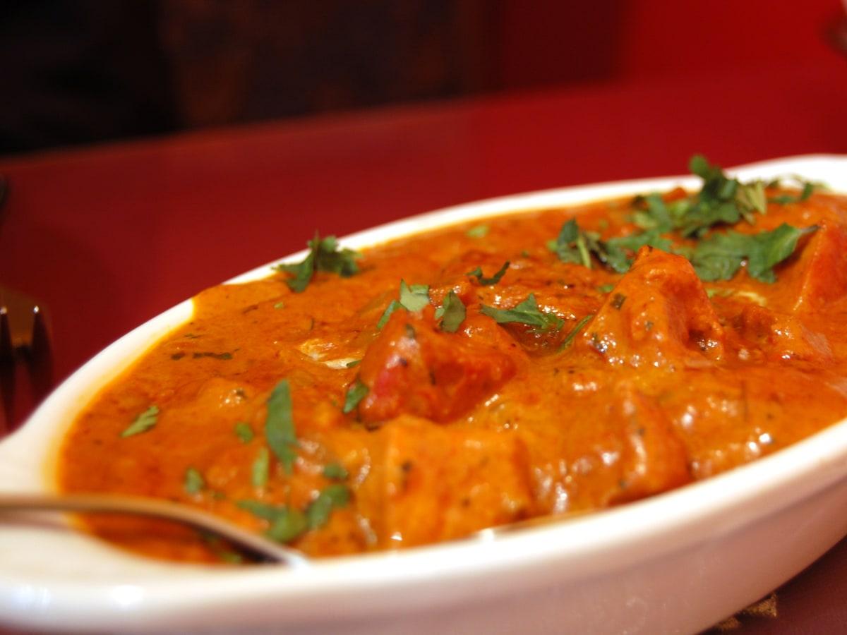 Schüssel mit Hähnchenstücken in einer kräftigen Orangen-Tomaten-Sahnesauce.