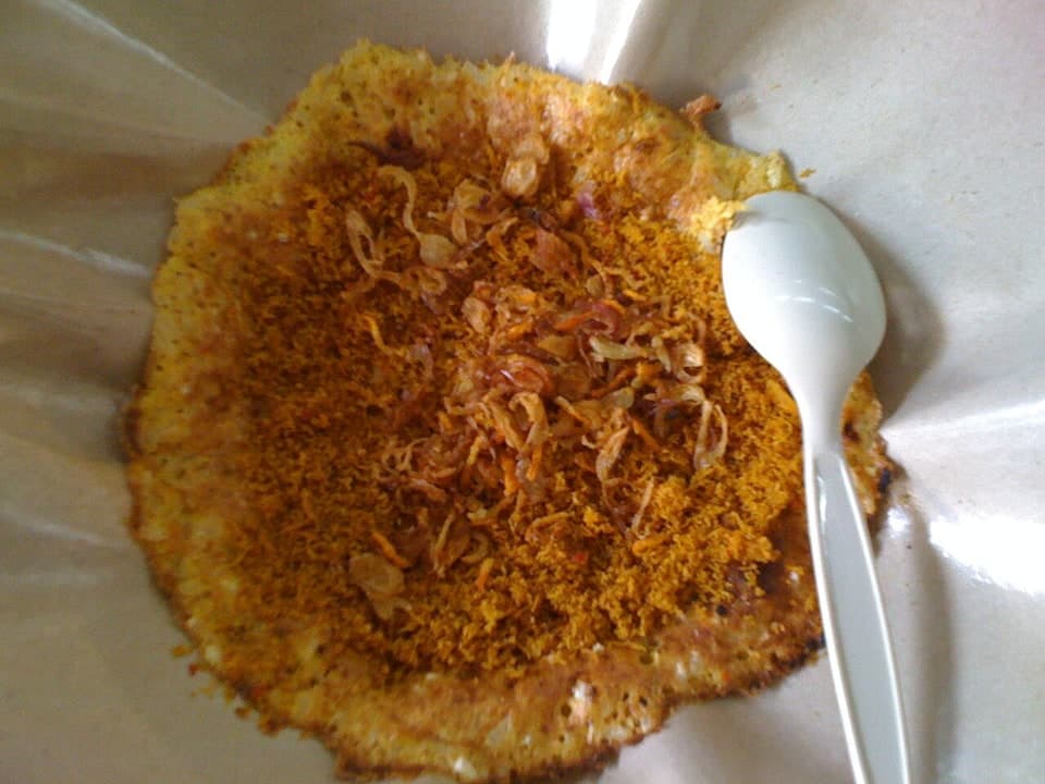 Snack croustillant d'œuf au riz gluant garni de noix de coco râpée et d'échalotes frites.