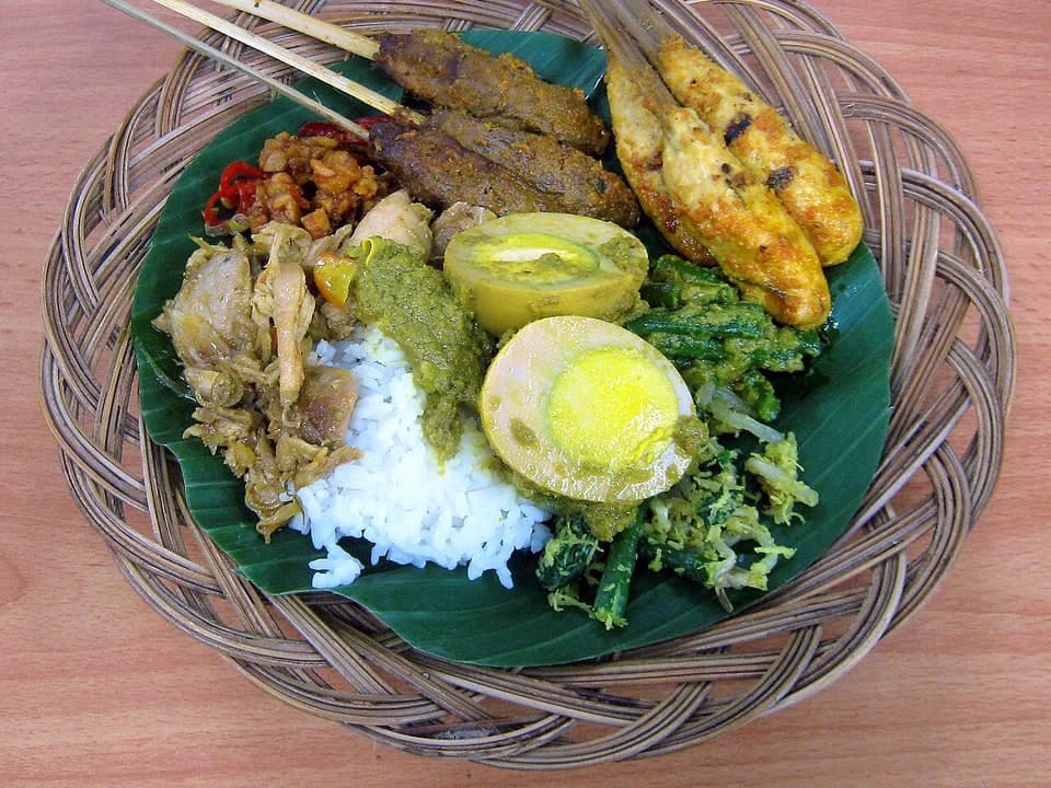 닭고기, 꼬치, 달걀, 채소, 삼발이 올려진 혼합 밥 접시.