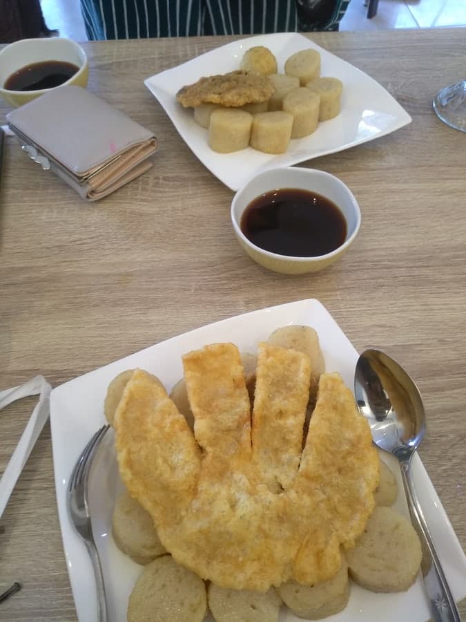 Teller mit geschnittenen Fischkuchen und Schalen dunkler Essigsauce.