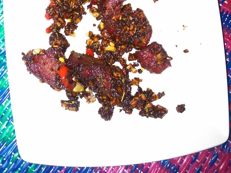 Irisan daging sapi asap berwarna merah gelap tersusun di permukaan polos.