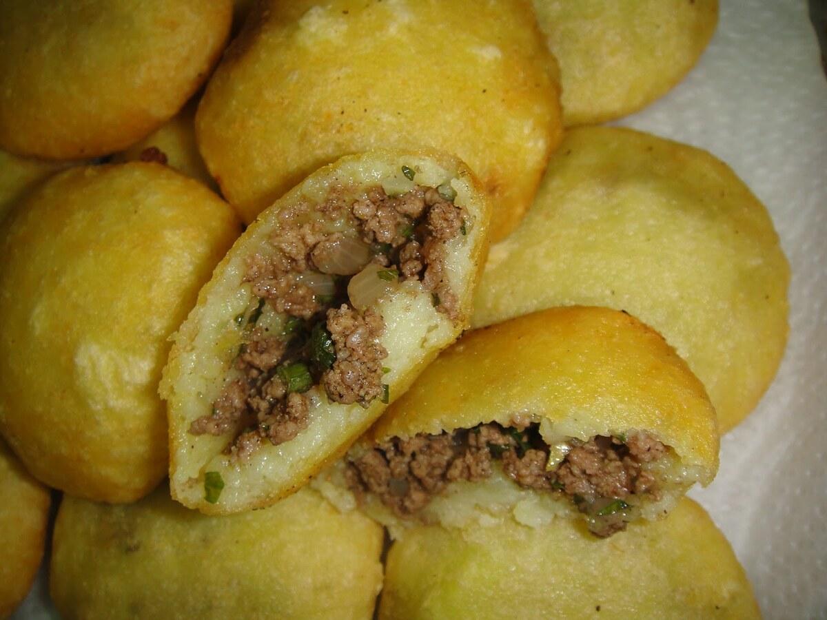 Goldene frittierte Knödel mit Reishülle, einer ist geöffnet und zeigt die gewürzte Hackfleischfüllung.