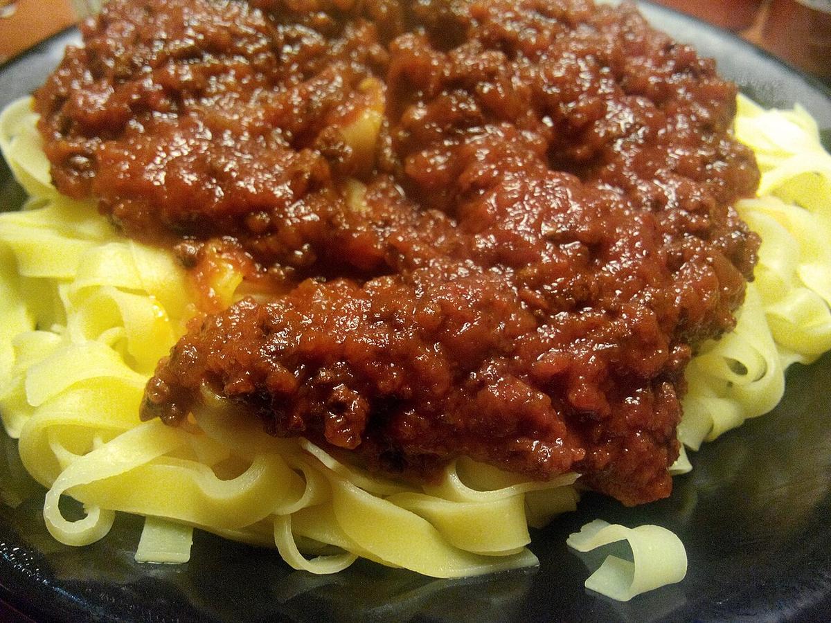 Teller mit breiten, mit Fleischragù überzogenen Eiernudeln.