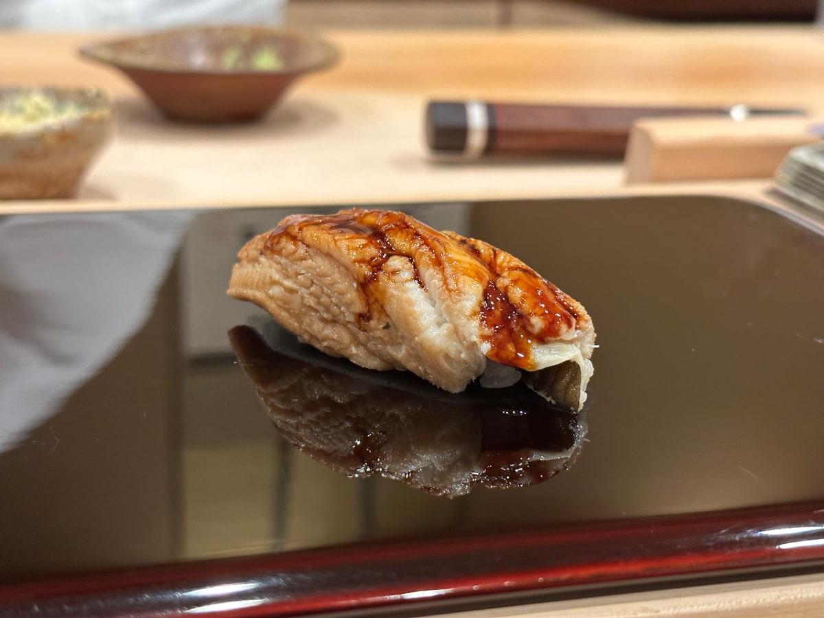 Seeaal-Nigiri auf einer Sushi-Theke mit glänzender Sauce über Reis.