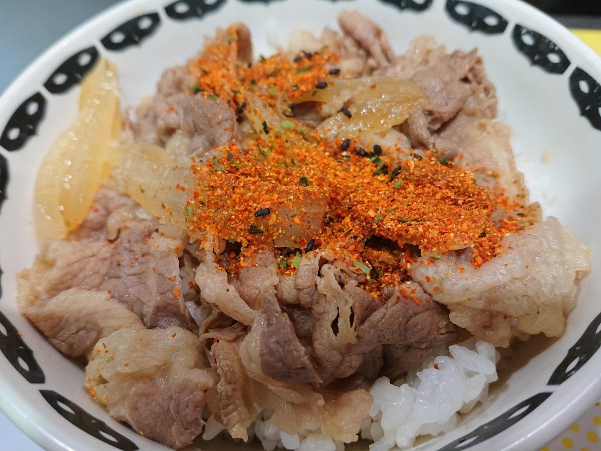 Semangkuk nasi dengan topping daging sapi tipis yang direbus, bawang bombay, dan acar jahe merah.