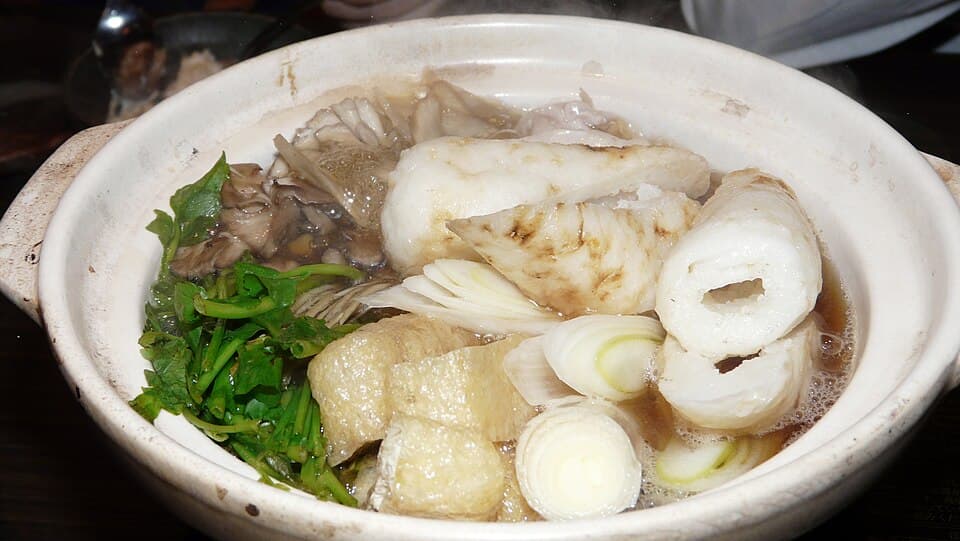 구운 쌀 막대기, 닭고기, 버섯, 채소, 육수가 담긴 전골 그릇.