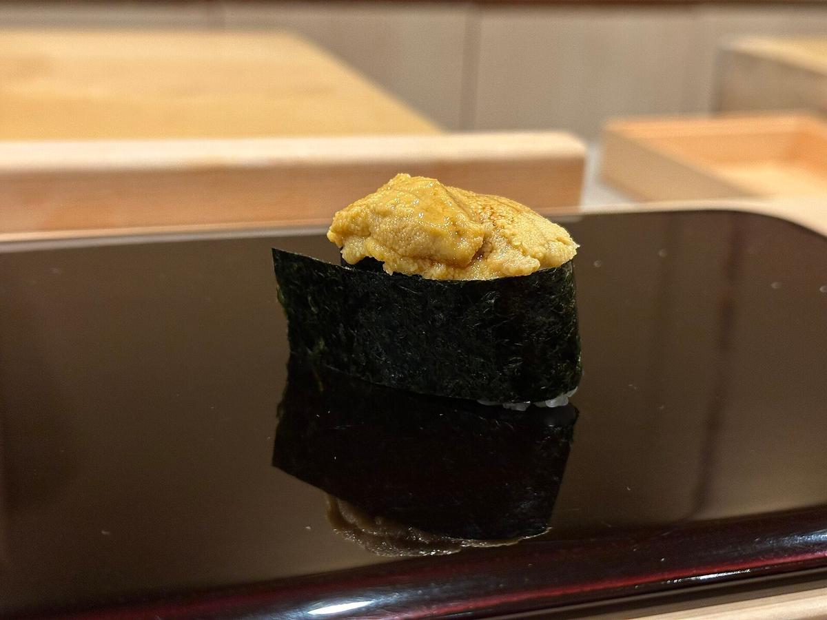 Seeigel-Gunkan-Sushi mit Nori auf einem dunklen Servierteller.
