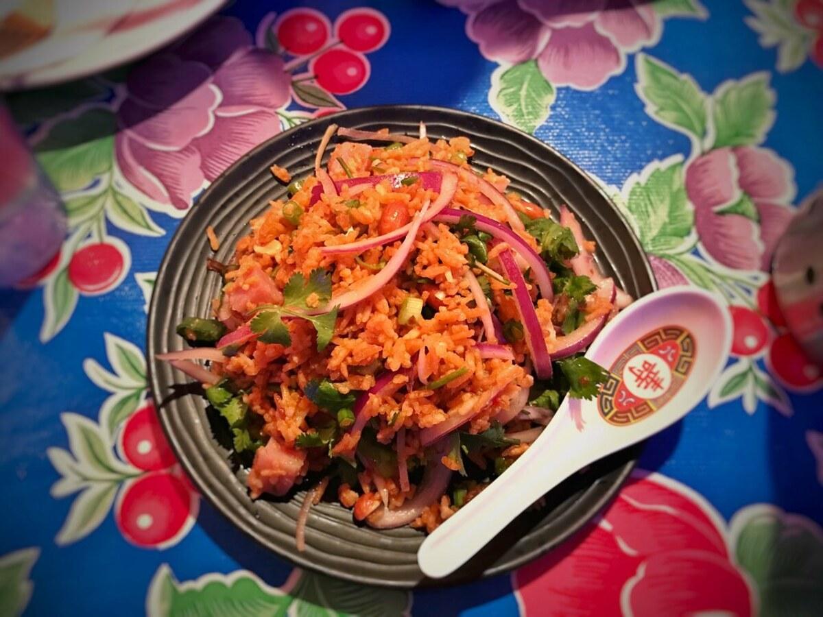 Knuspriger Reissalat mit Kräutern, Zwiebeln und knuspriger Garnitur auf einem schlichten Teller.