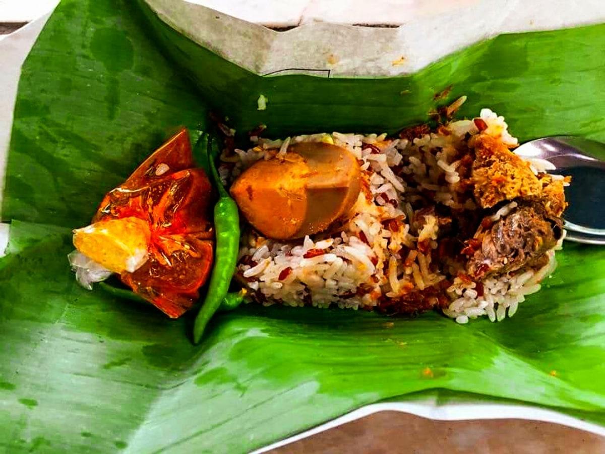 Bananenblatt-Teller mit Kokosreis, Fischcurry, eingelegtem Gemüse, Ei und Chilisambal.