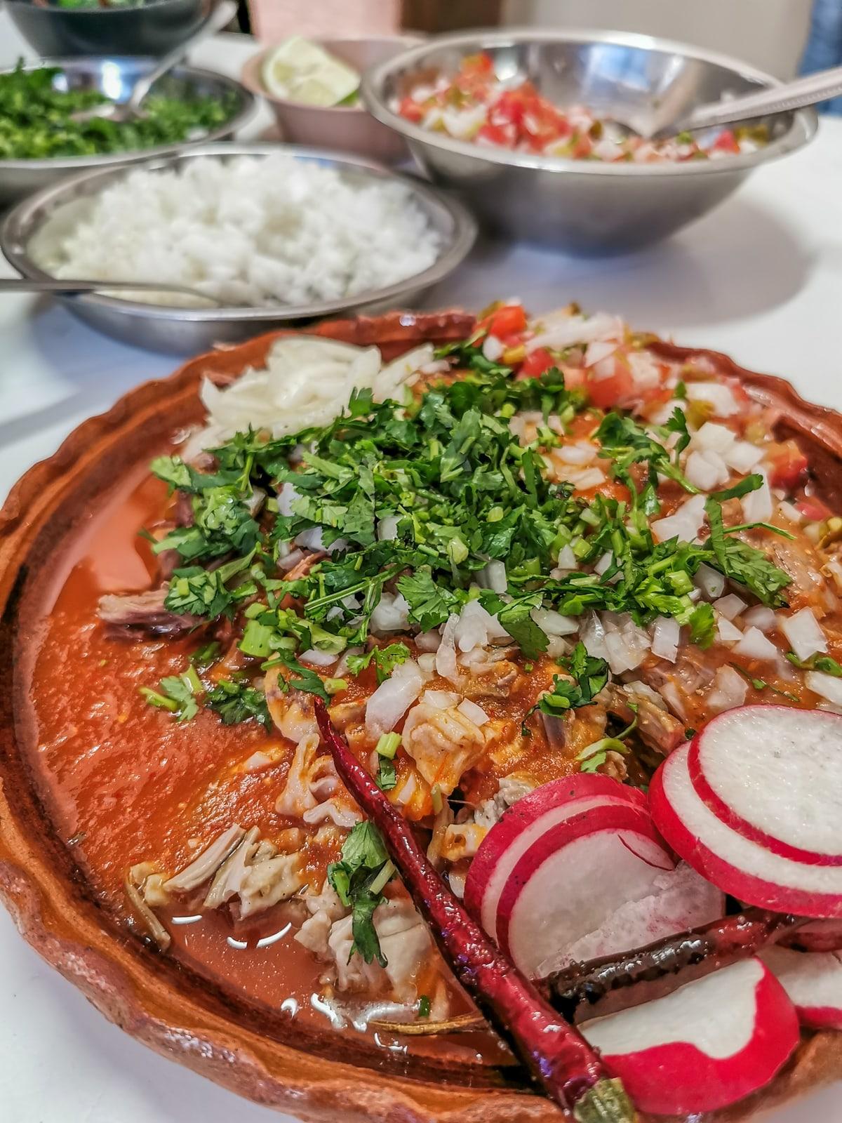 In rotem Chili geschmortes Rinderhackfleisch mit Zwiebeln, Koriander, Radieschenscheiben und Limette.