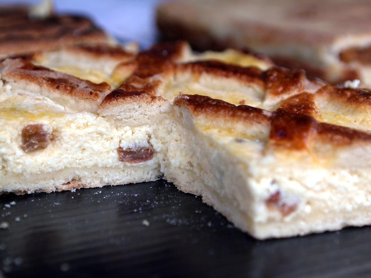Irisan kue isi keju dengan bagian atas serpihan kecoklatan dan isian krim.