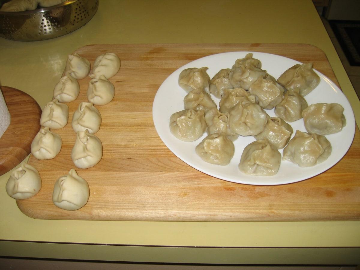Plate of steamed pleated meat dumplings on a wooden table.