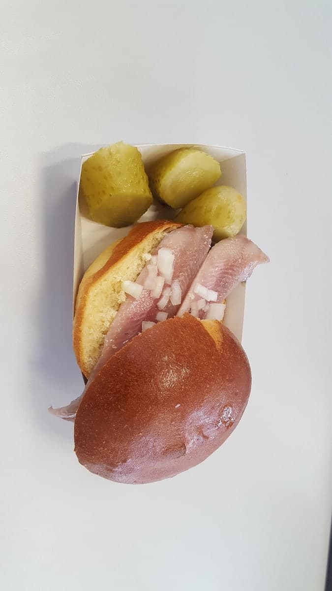 Weiches Brötchen gefüllt mit gepökeltem Hering, gehackten Zwiebeln und Gurkenscheiben.