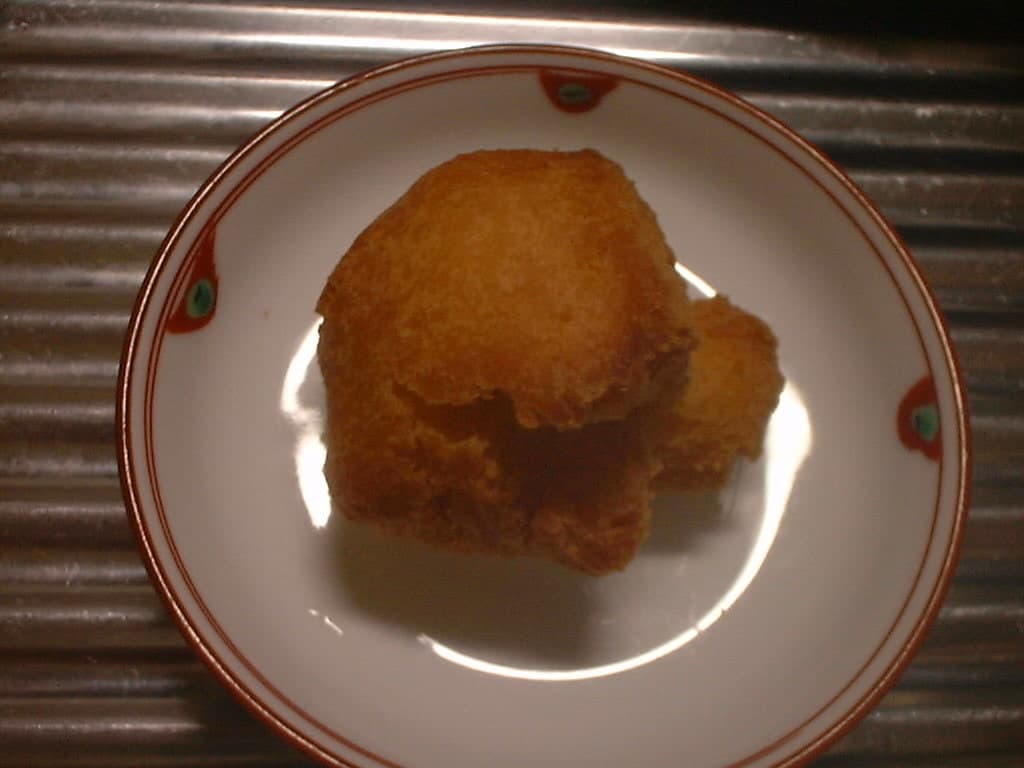 Bola de massa frita dourada em um pequeno prato.