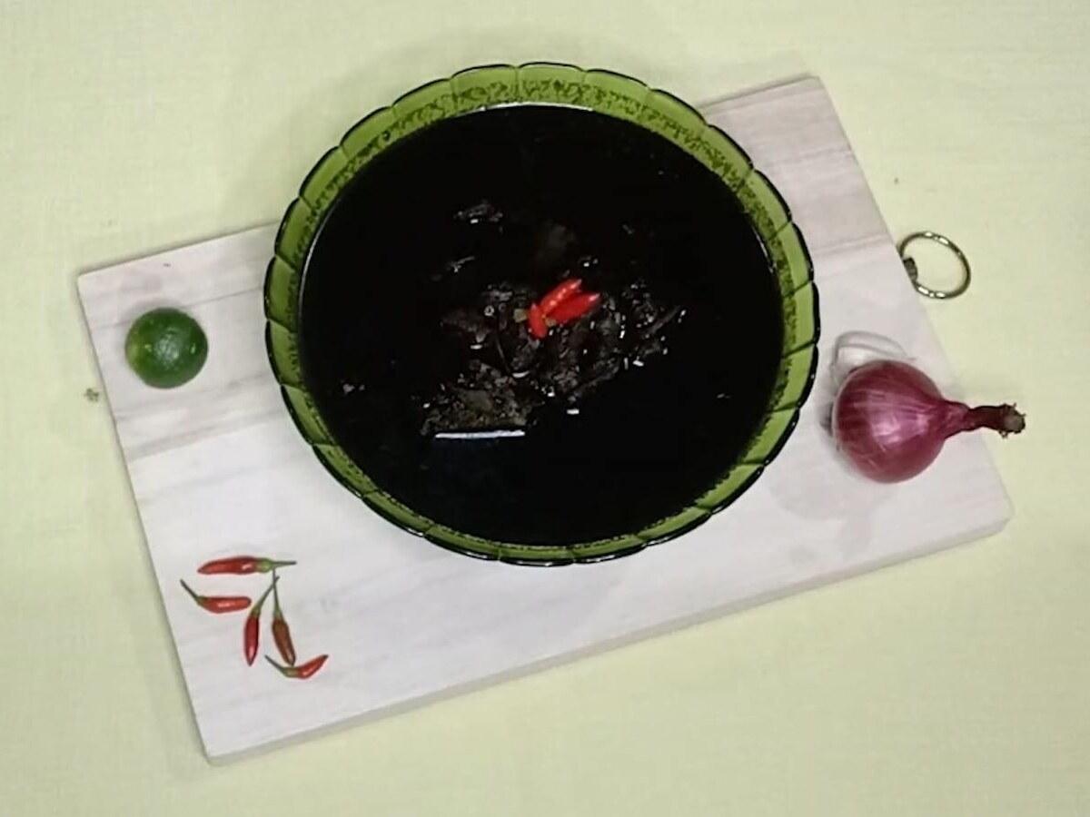 肉の塊とハーブが入った濃い色の牛肉スープが器に盛られている。