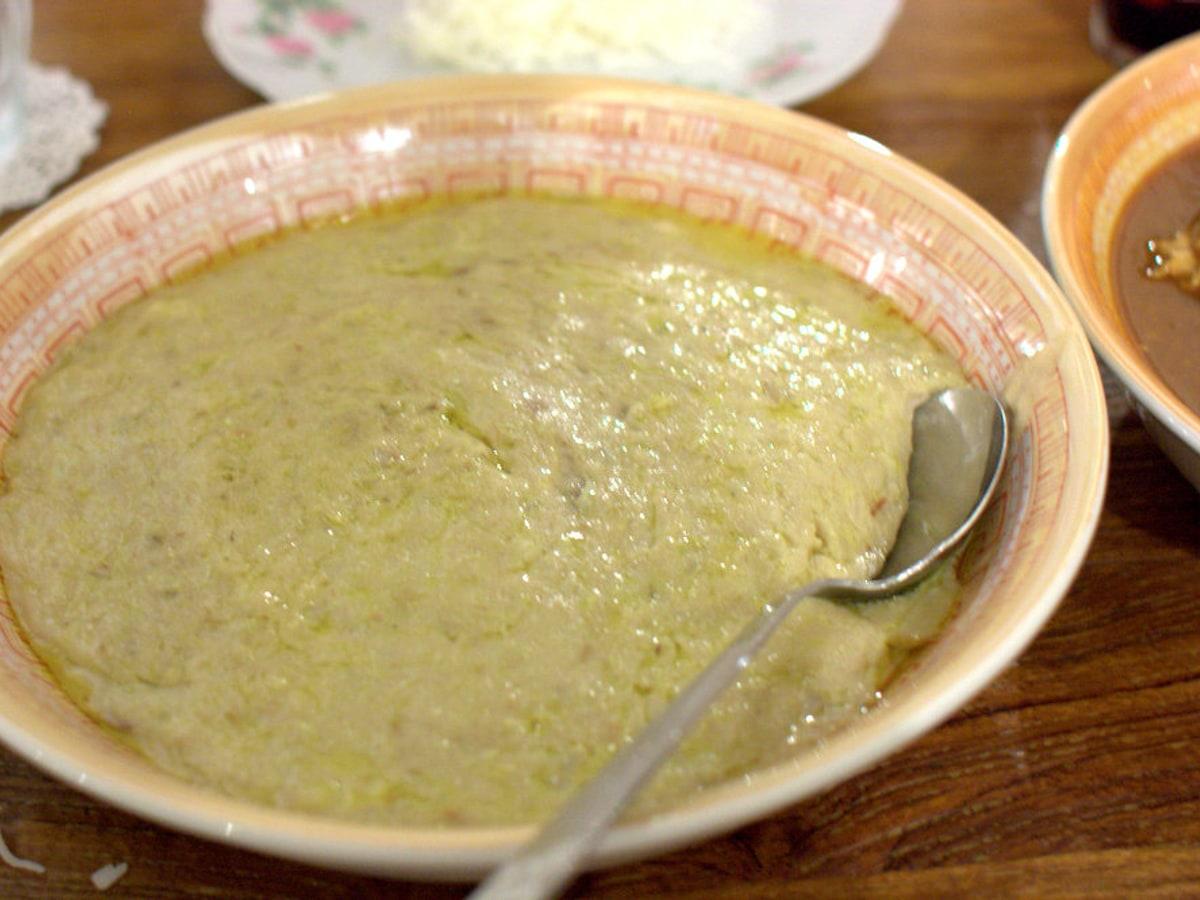 A shallow bowl of smooth pale wheat-and-meat porridge with a spoon.