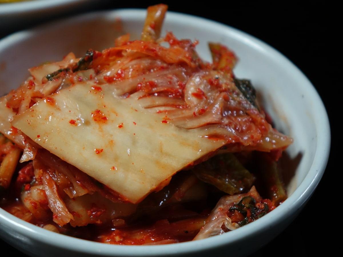Bowl of red seasoned napa cabbage kimchi pieces.