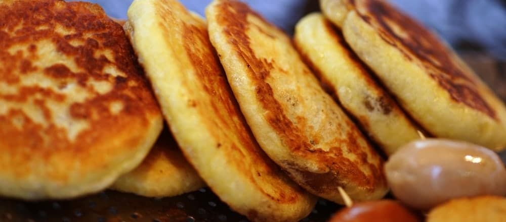 Mehrere gebräunte, süß gefüllte Pfannkuchen nebeneinander auf einer Grillplatte.