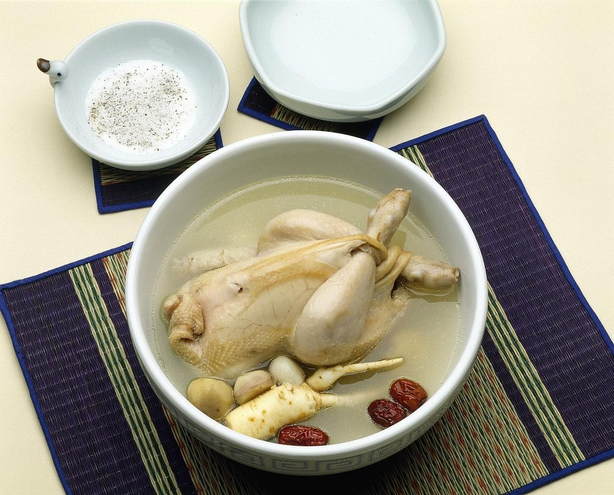 Ganze Hühnersuppe mit Reis und Jujubes in einer weißen Schüssel.