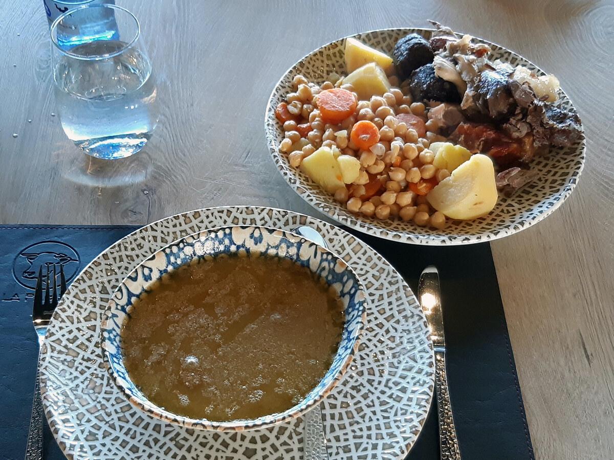 테이블 위에 병아리콩, 고기, 채소, 육수 구성 요소가 담긴 접시.