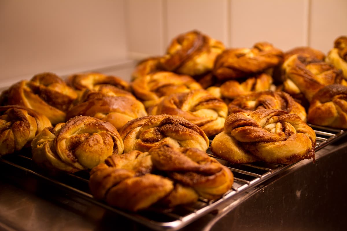 Tablett mit goldenen, gekringelten Zimtschnecken, die auf einem Gitter abkühlen.
