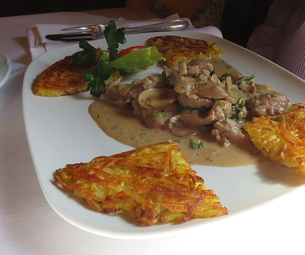 Plate of creamy veal strips with mushrooms and crisp grated potatoes.