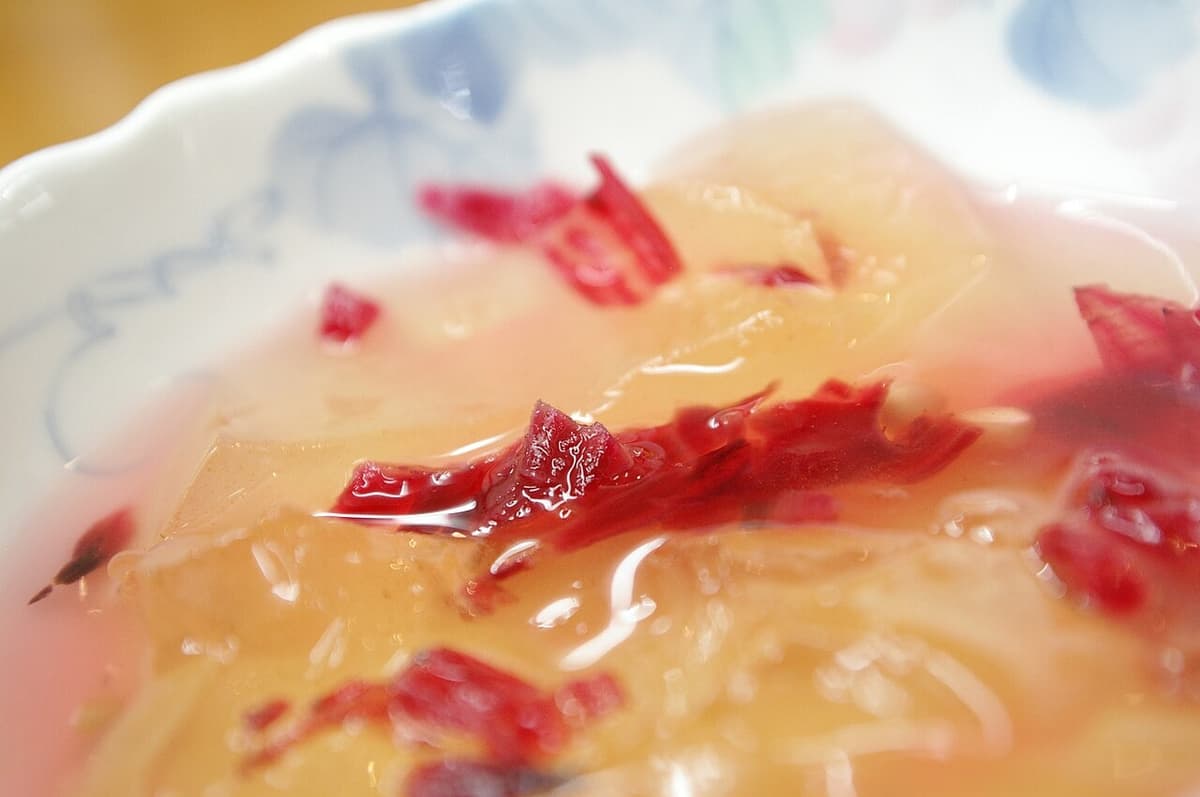 Blasses Gelee in Sirup mit roter Garnitur in einer Schale.