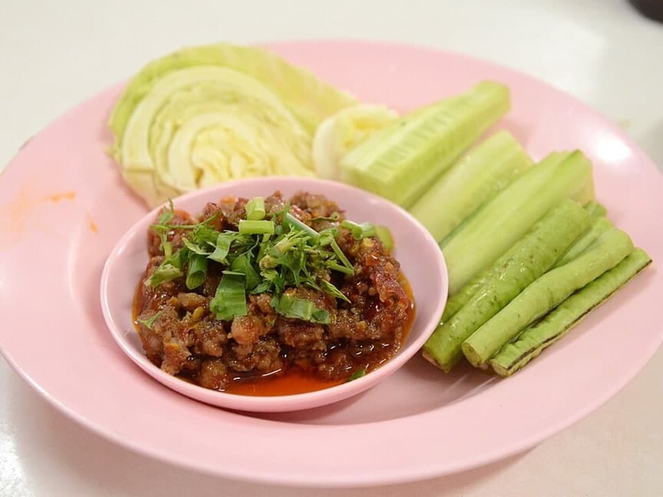 Tomatenrotes Schweinefleisch-Relish in einer kleinen Schale mit geschnittenem Kohl und Gemüse.