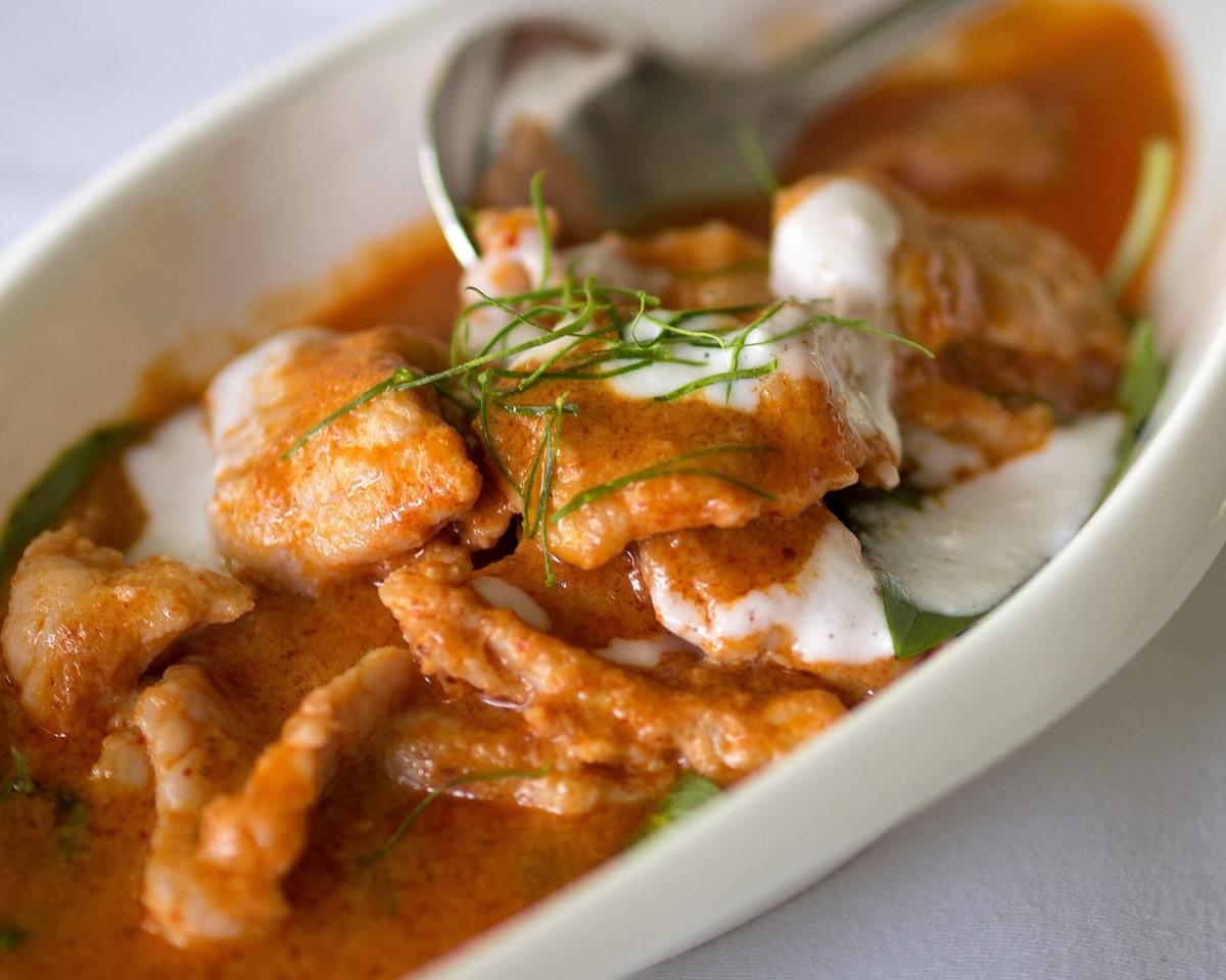 Schüssel mit dickem Orangen-Kokos-Curry mit Fleisch, Reis und geriebenen Limettenblättern.
