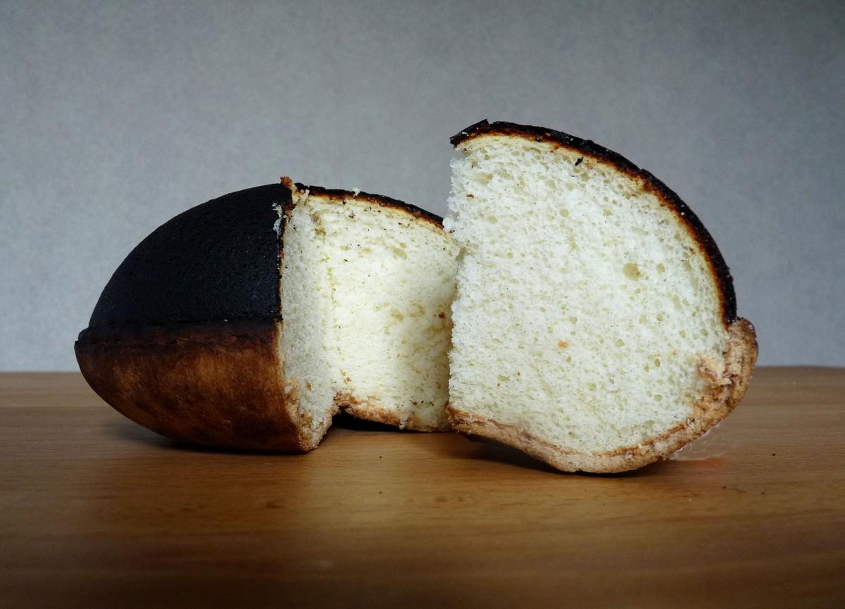 Kue keju berbentuk kubah hitam dipotong untuk menunjukkan bagian dalamnya yang pucat.