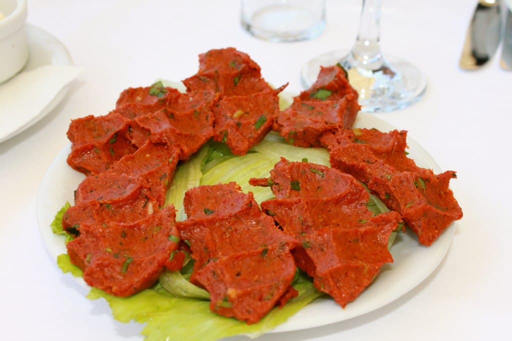 Rote Bulgur-Patties auf Kopfsalatblättern angeordnet.