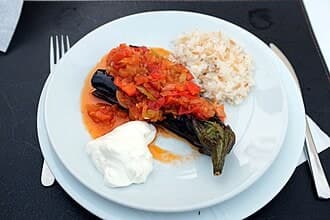 Gefüllte Aubergine mit Tomaten-Zwiebel-Füllung, serviert mit Reis und Joghurt.