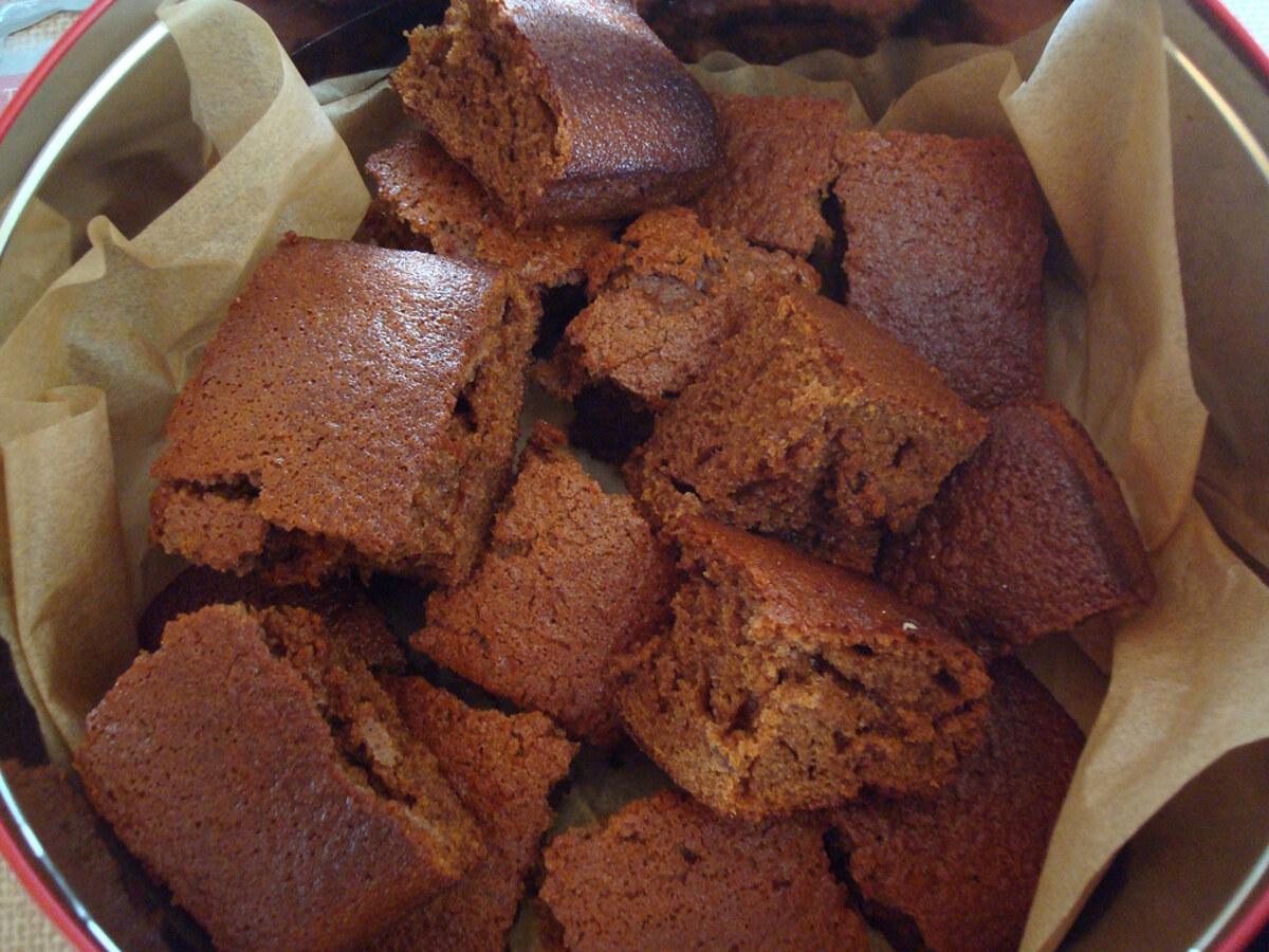 Carrés de gâteau sombre, collant, à l’avoine et au gingembre empilés dans un plat garni de papier.