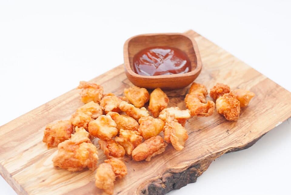 Fried cheese curds served with a small cup of dipping sauce.