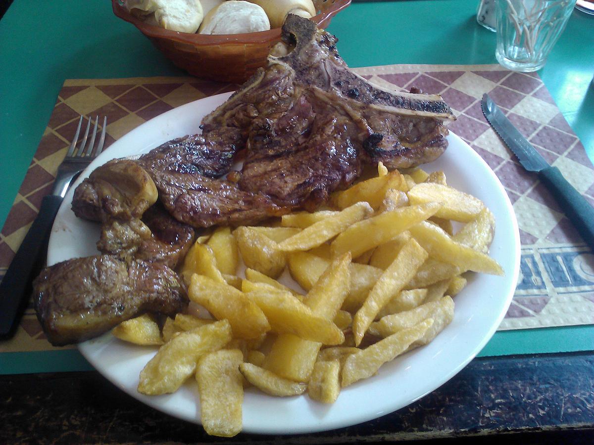 Grilled cross-cut beef ribs served on a plate with fried potatoes.