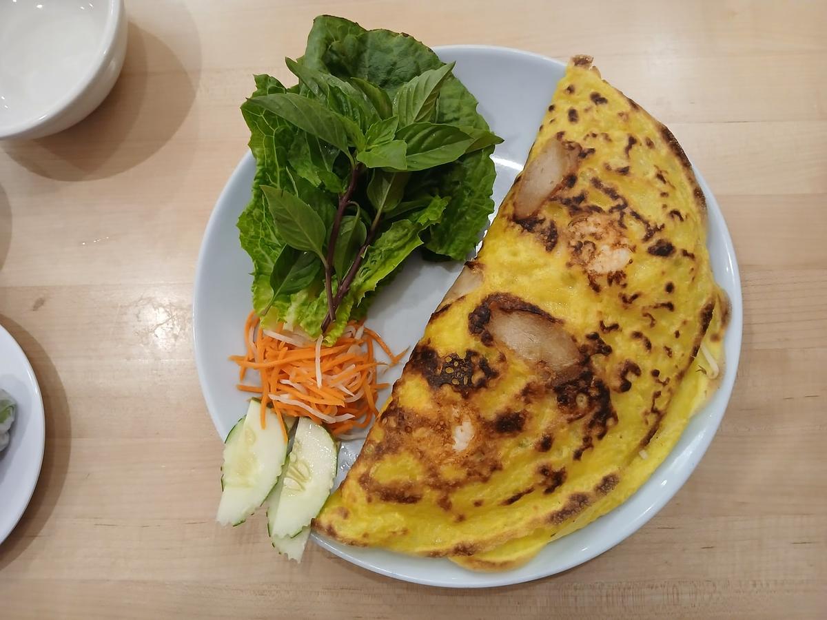 Knusprige, gefaltete Reisteigcrepe, serviert mit Kräutern, Gemüse und Dipsauce.