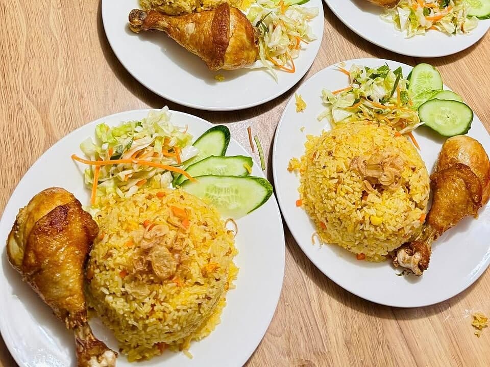 أرز ذهبي مغطى بالدجاج المقطع، الأعشاب، البصل والصلصة.